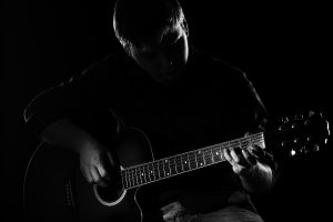 Man with guitar in the darkness
